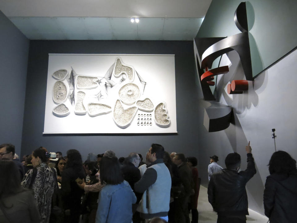 En esta fotografía del 7 de diciembre de 2019 visitantes observan la piezas "Centro del lado oeste" (2019) y "Canto al océano" (1963) del artista mexicano Manuel Felguérez en la exposición "Trayectorias" del Museo Universitario de Arte Contemporáneo de la Universidad Nacional Autónoma de México (UNAM) en la Ciudad de México. La exposición celebra la trayectoria de Felguérez quien cumple 91 años este mes. (Foto AP/Berenice Bautista)