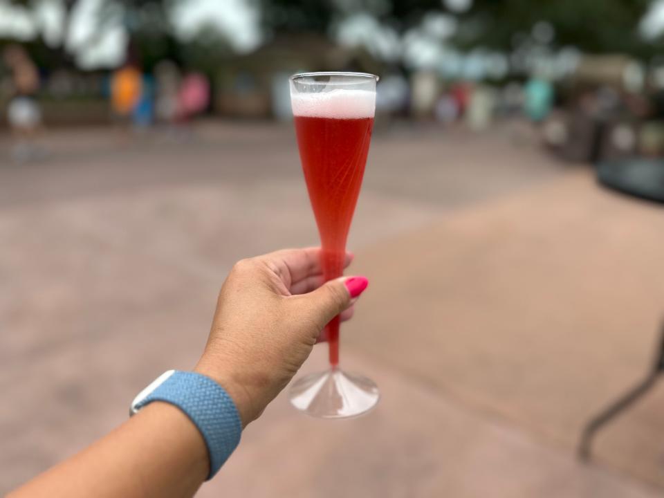 hand holding flute of beer mimosa from epcot food and wine