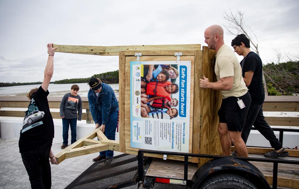 Gateway High School students, from left, Quinton Molnar, Caleb Anderson and Christian Champ, far right, help their carpentry teacher, J.T. Schurr , front right, drop off a life jacket loaner station at Lovers Key State Park on Thursday, Jan. 4, 2024. The stand was built by the students at Gateway High School in partnership with Lee Health and others. Tina Fleming, a injury prevention specialist with Safe Kids Worldwide at Golisano Children's Hospital secured grants to get six stands built. Two are already placed. The stations offer life jackets to those who need them while visiting area beaches. Several Life jacket stands were lost in Hurricane Ian. It also offers the students to practice a trade they may be interested in pursing after high school. Peyton Anderson is second from left.