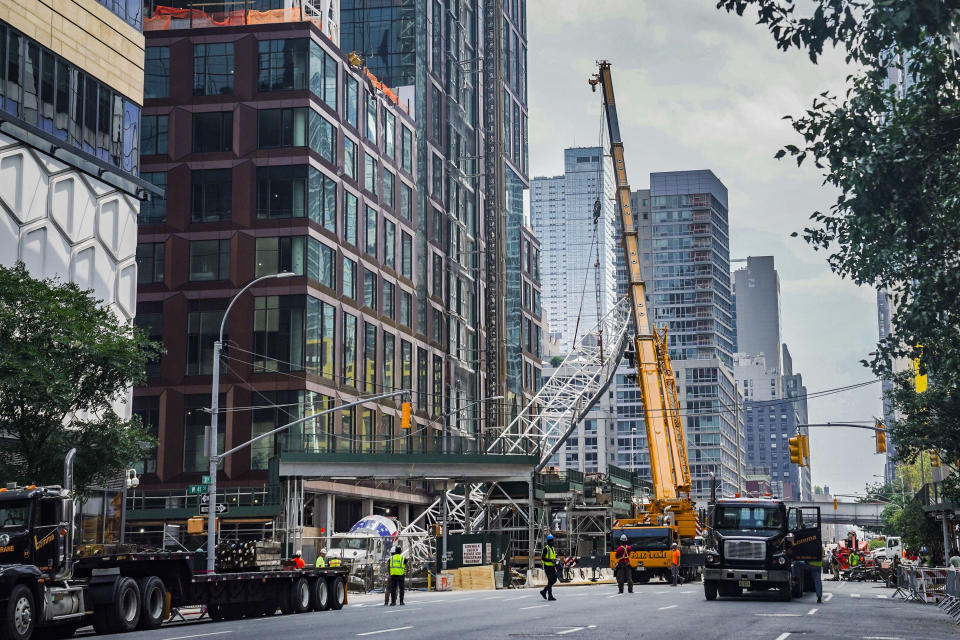 A ground crane lifts the extension arm from a hi-rise construction crane, which broke away yesterday and plummeted to the street after the crane caught fire, Thursday July 27, 2023, in New York. (AP Photo/Bebeto Matthews)