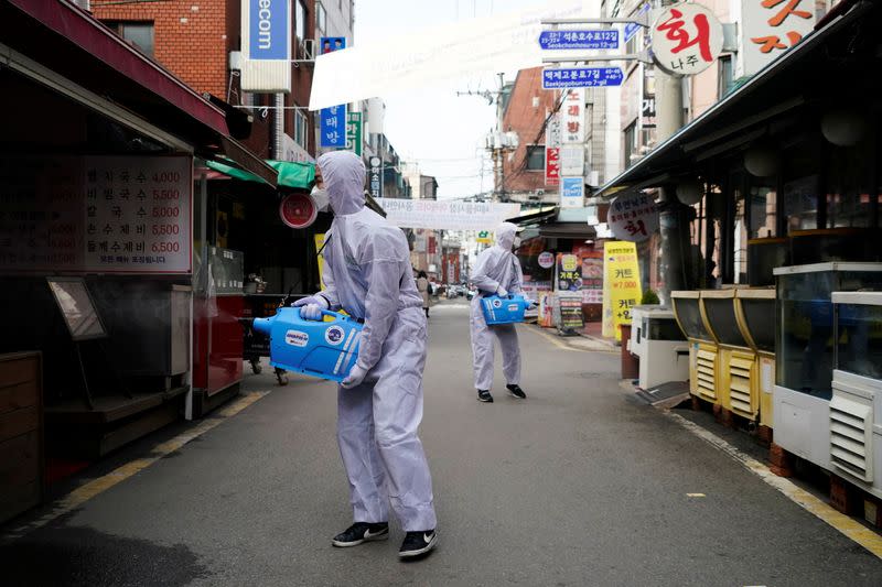 Employees from a disinfection service company sanitize a traditional market in Seoul