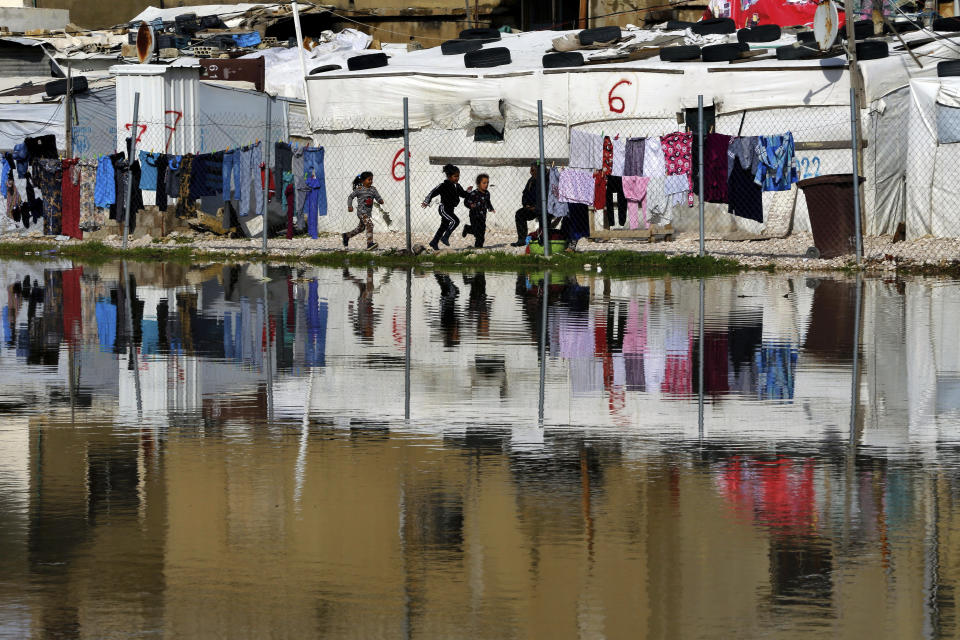 Syrian refugee children play outside as their tents are reflected in a pool of rain water at a refugee camp, in the town of Bar Elias, in the Bekaa Valley, Lebanon, Thursday, Jan. 10, 2019. A storm that battered Lebanon for five days displaced many Syrian refugees after their tents got flooded with water or destroyed by snow. (AP Photo/Bilal Hussein)