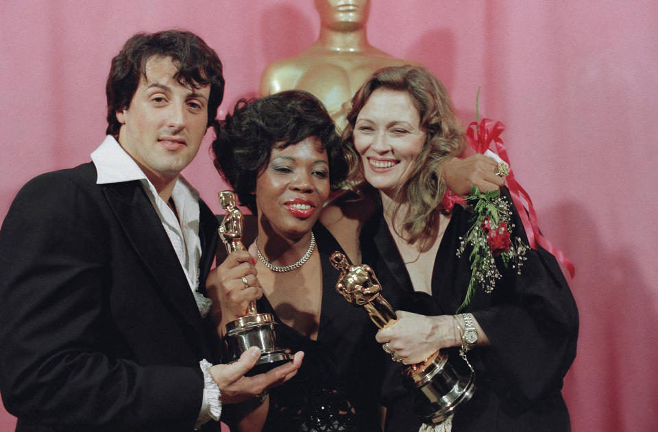 FILE - In this March 28, 1977, file photo, Sylvester Stallone, left, holds his Oscar for his performance in "Rocky," Eletha Finch, center, holds the Oscar she accepted for her late husband, Peter Finch, who was named best actor for his performance in "Network," and Faye Dunaway holds the Oscar she won for best actress in "Network," at the Oscars in Los Angeles. “Hoosiers” shot all the way to No. 1 in The Associated Press Top 25 of best sports movies, narrowly edging Academy Award Best Picture honoree “Rocky” -- released in 1976. (AP Photo/George Brich, File)