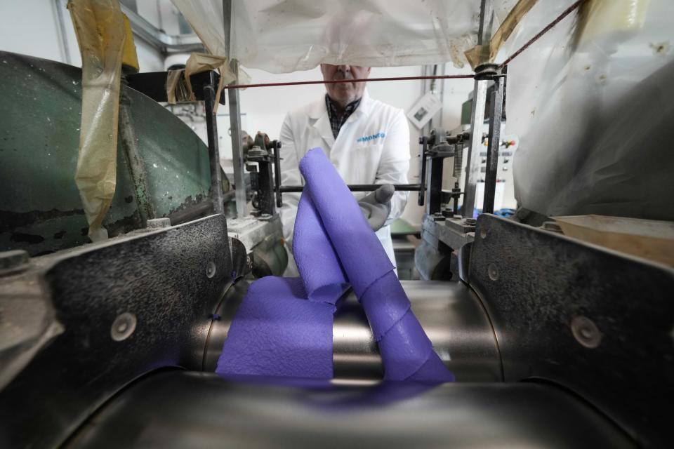 A worker fixes a surface portion of an athletics track, at the Mondo factory, in Alba, northern Italy, Wednesday, March 13, 2024. The athletics track for the upcoming Paris Olympics is being produced by the Mondo company at its factory in northern Italy. The track is made in portions, rolled up and then will be transported to the Stade de France, where it will be installed over the next month. (AP Photo/Luca Bruno)