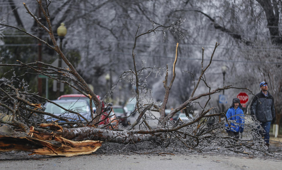 People walk past a fallen limb on Thursday, Feb. 3, 2022 in Memphis, Tenn. A major winter storm that already cut electric power to about 350,000 homes and businesses from Texas to the Ohio Valley was set to leave Pennsylvania and New England glazed in ice and smothered in snow.(Patrick Lantrip/Daily Memphian via AP)