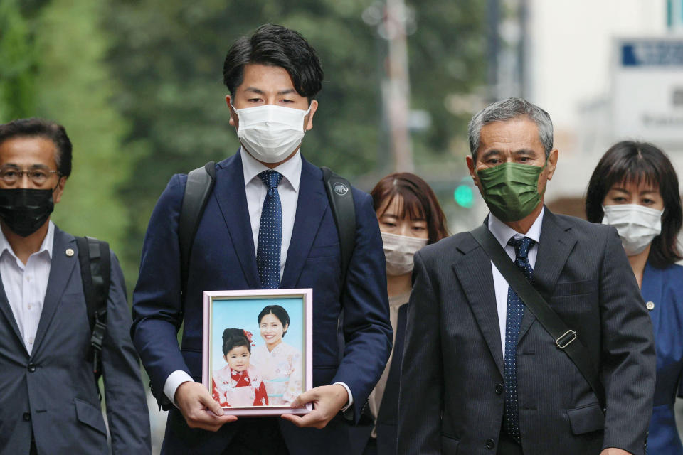 Takuya Matsunaga, second from left, holding a portrait of his wife Mana Matsunaga and daughter Riko Matsunaga, who were killed in a car accident in 2019, walks toward Tokyo District Court to hear the court's ruling on the driver Kozo Iizuka, in Tokyo Thursday, Sept. 2, 2021. The court on Thursday sentenced Iizuka, a 90-year-old former top bureaucrat, to five years in prison in the fatal car accident on a busy Tokyo street in a high-profile case in a fast-aging country where elderly driving has become a major safety concern. (Shinji Kita/Kyodo News via AP, File)(Kyodo News via AP)