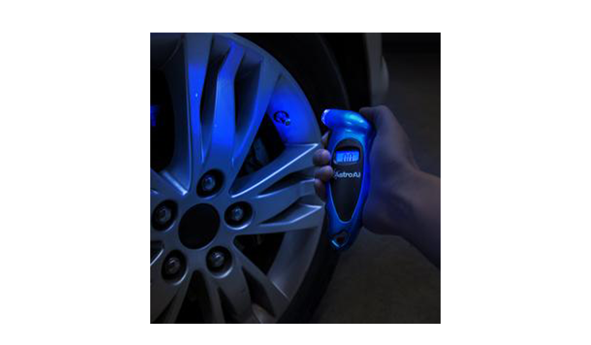 Person checking tire pressure at night, gauge lit up