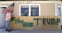 <p>John Murray attaches a U.S. flag to a sign reading “Bet They Blame Trump” at his business damaged in the wake of Hurricane Harvey, Tuesday, Aug. 29, 2017, in Rockport, Texas. Murray created the sign in hopes President Donald Trump would visit Rockport during his Texas visit, but he did not expect him to make the trip. (Photo: Photo: Eric Gay/AP) </p>