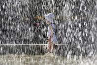 Ein Kleinkind spielt vor der Alten Oper in Frankfurt am Main unter einer Wasserfontäne. (Bild: Michael Probst/AP)