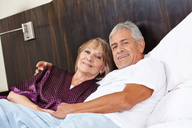 Senior couple in love cuddle in a hotel bed