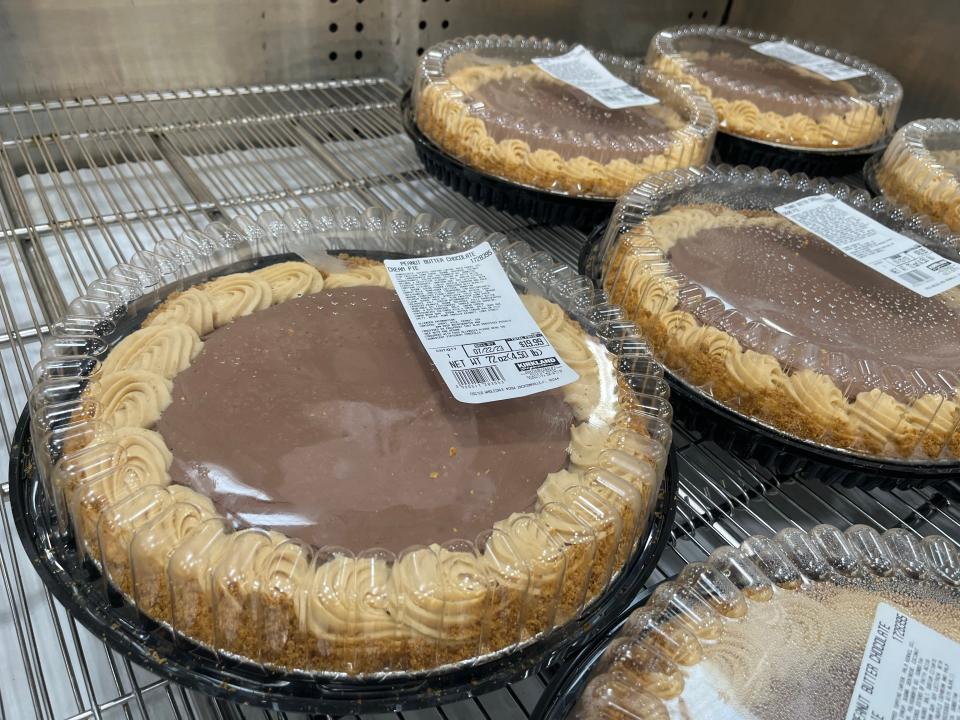 A fridge display in Costco with a few chocolate-peanut butter pies in plastic packaging