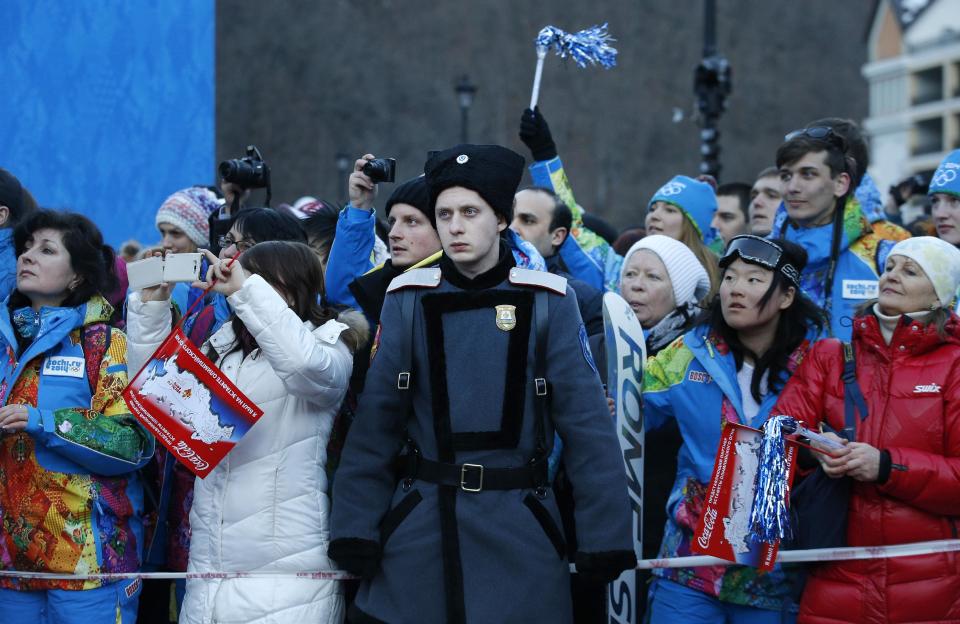 A Cossack stands on guard as people try to get a glimpse of the Olympic torch as it makes it's way throughout the streets of the Rosa Khutor ski resort in Krasnaya Polyana, Russia at the Sochi 2014 Winter Olympics, Wednesday, Feb. 5, 2014. (AP Photo/Christophe Ena)