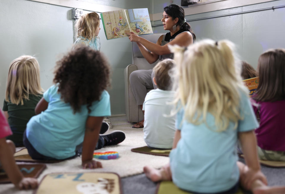 Kiera Holthusen reads a book at Bumble Art Studio day care center in Astoria, Ore., Friday, Sept. 2, 2022. From Oregon to New York, demand for child care far exceeds supply. Families are growing increasingly desperate as providers deal with staffing shortages exacerbated by the coronavirus pandemic as well as historically low pay worsened by inflation. (AP Photo/Craig Mitchelldyer)