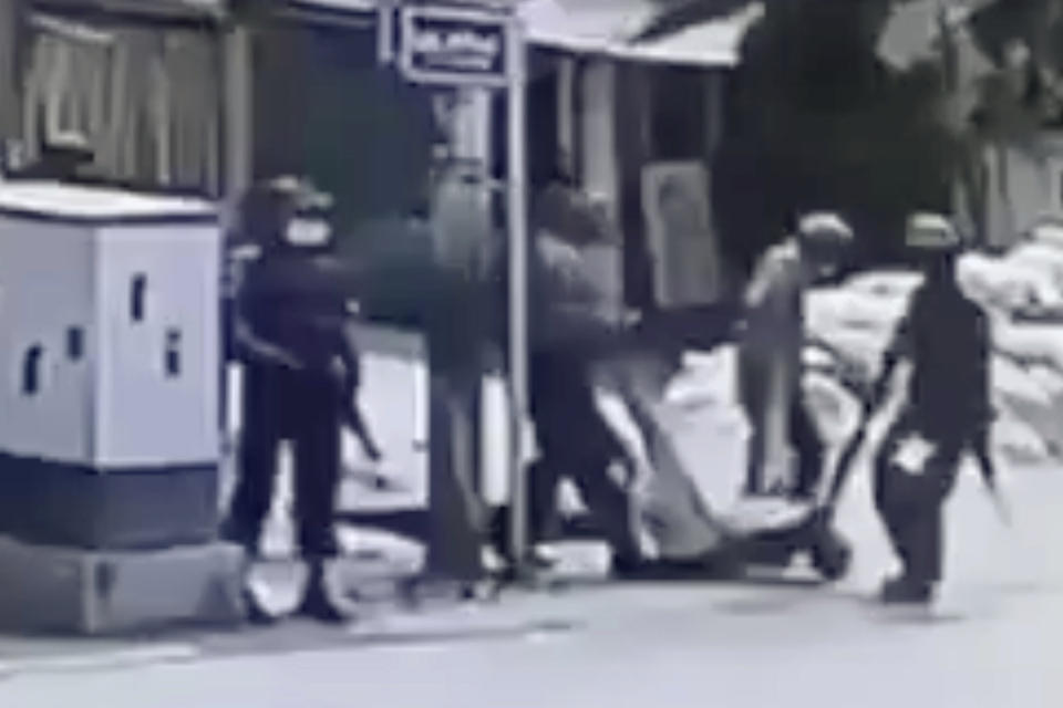 In this March 13, 2021 image from video obtained by The Associated Press, security forces carry the body of an unidentified individual in the Sein Pann ward of Mandalay, Myanmar. Access to technology and social media have allowed members of the public to create a body of real-time evidence that contradicts the state narrative and could eventually be used to help build an international criminal case while also making it difficult for foreign donors and developed nations to turn a blind eye to mounting atrocities. (AP Photo)