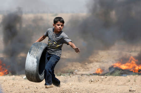 A Palestinian boy carries a tire during a protest marking al-Quds Day, (Jerusalem Day), at the Israel-Gaza border, east of Gaza City June 8, 2018. REUTERS/Mohammed Salem