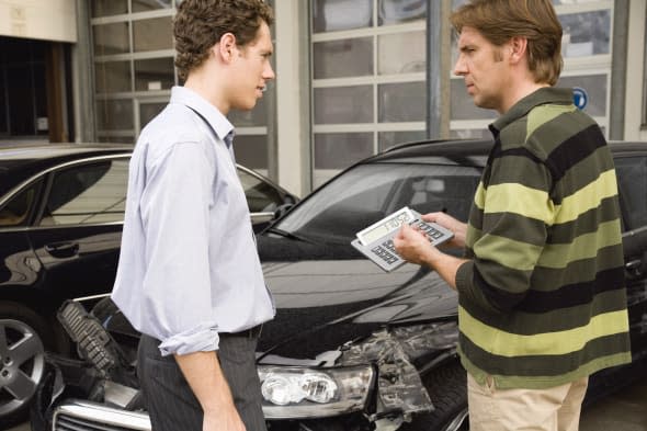 Insurance adjuster assessing damage to car