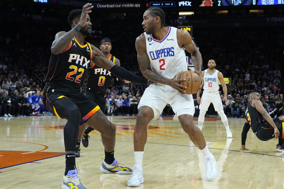 Los Angeles Clippers forward Kawhi Leonard (2) looks to pass under pressure from Phoenix Suns center Deandre Ayton (22) during the first half of Game 2 of a first-round NBA basketball playoff series, Tuesday, April 18, 2023, in Phoenix. (AP Photo/Matt York)