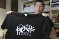Designer Susumu Kikutake shows anti-Olympics T-shirt during an interview with the Associated Press in Tokyo, Wednesday, June 9, 2021. An online article showcasing his design calling for the Olympics to be cancelled resulted in harsh online comments, and he sold only around 10 shirts a month before the pandemic. But demand for the t-shirts has boomed in the past two months, with sales reaching 100 shirts in April and 250 in May. The characters on the shirt read "Cancelation, Cancelation". (AP Photo/Koji Sasahara)