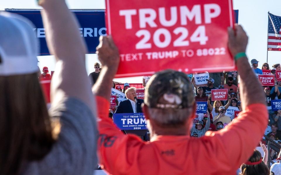 Supporters held signs as Mr Trump spoke at the rally - Sergio Flores/Bloomberg