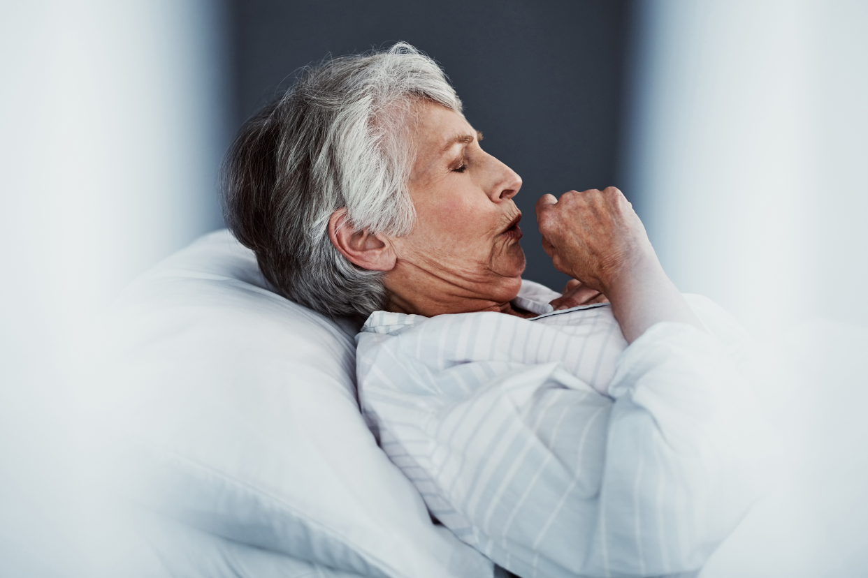 Woman coughing in a hospital bed