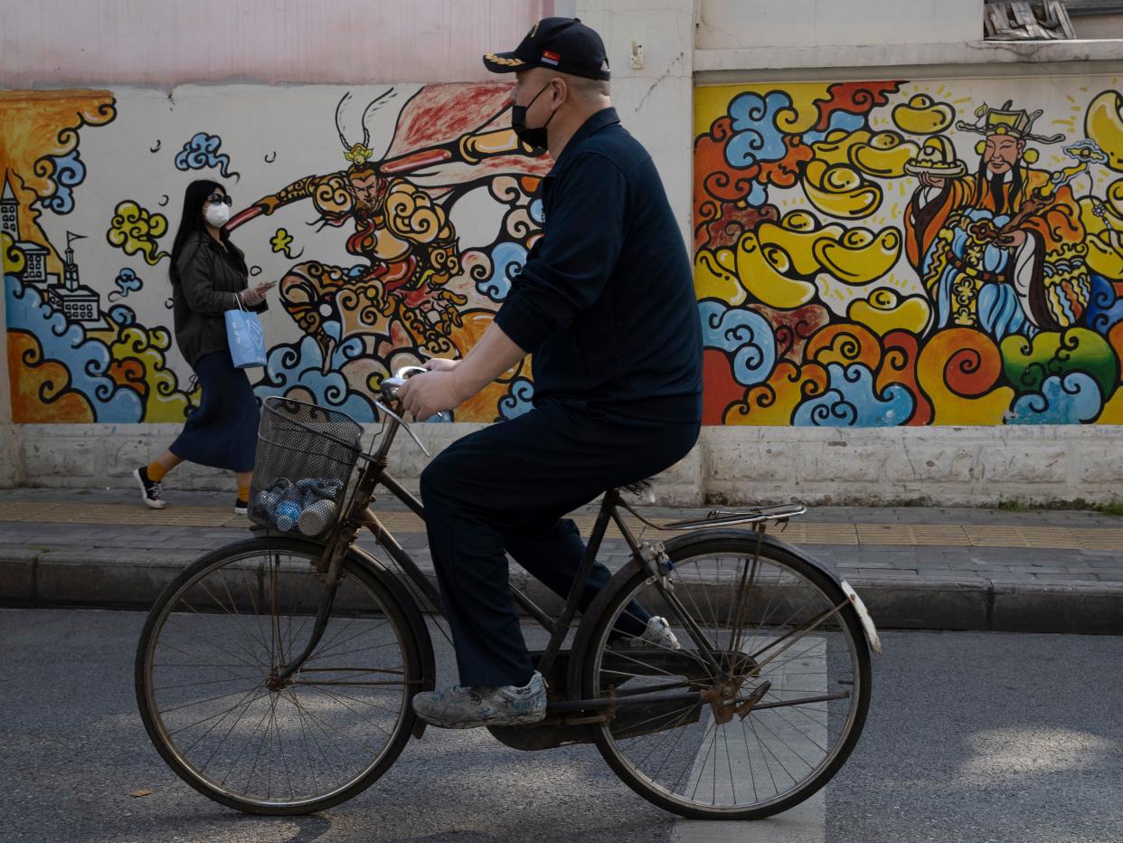 Residents wearing masks against the coronavirus past by wall mural in Wuhan in central China's Hubei province on Thursday, April 9, 2020. (AP Photo:Ng Han Guan)  