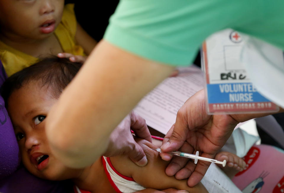 FILE - In this Feb. 16, 2019, file photo, Philippine National Red Cross and Health Department volunteers conduct house-to-house measles vaccination to children at an informal settlers community in Manila, Philippines. The Philippine health secretary says 136 mostly children have died of measles and 8,400 others have been downed by the contagious viral disease in an outbreak partly blamed on a vaccination scare in recent years. (AP Photo/Bullit Marquez, File)