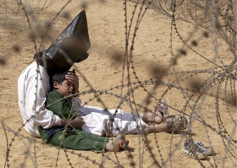 FILE - An Iraqi prisoner of war comforts his 4-year-old son at a regroupment center for POWs of the 101st Airborne Division near An Najaf, March 31, 2003. The man was seized in An Najaf with his son, and the U.S. military did not want to separate father and son. (AP Photo/Jean-Marc Bouju, File)