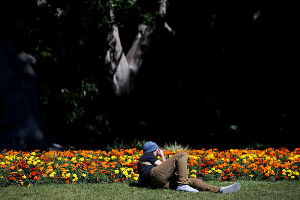 A man lays in the sun at Hyde Park in Sydney, Australia. 