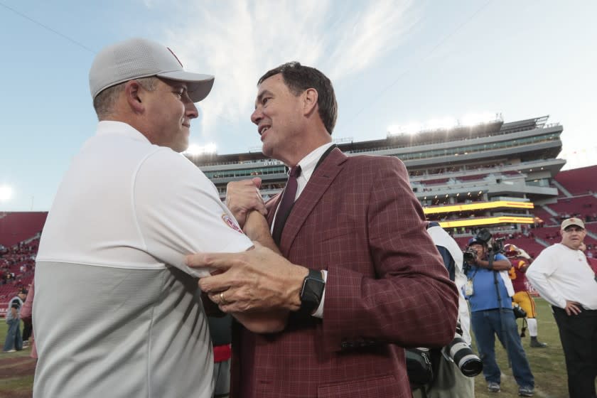 USC coach Clay Helton is congratulated by athletic director Mike Bohn at midfield after a 52-35.