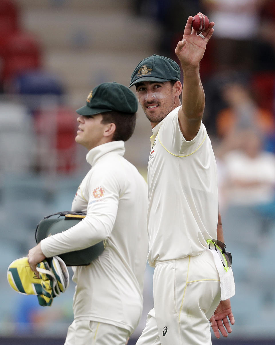 Australia's Mitchell Starc, right, holds up the ball after taking 10 Sri Lankan wickets in their cricket test match in Canberra, Monday, Feb. 4, 2019. Australia won the test by 366 runs and the series 2-0. (AP Photo/Rick Rycroft)