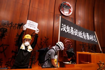 A person holds a placard next to a banner displayed inside a chamber, after protesters broke into the Legislative Council building during the anniversary of Hong Kong's handover to China in Hong Kong