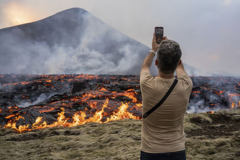 Un hombre toma fotografías mientras la lava emerge de una fisura del volcán Fagradalsfjall cerca de la montaña Litli-Hrútur