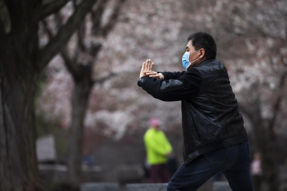 Zhili Sun, practices tai chi by blooming cherry trees while wearing a mask, Sunday, March 15, 2020, along the tidal basin in Washington. Sun, who is from China, says he was visiting his son in the U.S. when the coronavirus pandemic struck and has been unable to get home. (AP Photo/Jacquelyn Martin)