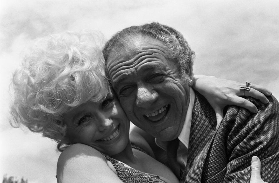 British comedy actor Sid James gets a friendly farewell cuddle from his British co-star Barbara Windsor as they complete the last day of shooting of the film "Carry On Girls", at Pinewood Studios, England, May 25, 1973. (AP Photo/Robert Dear)