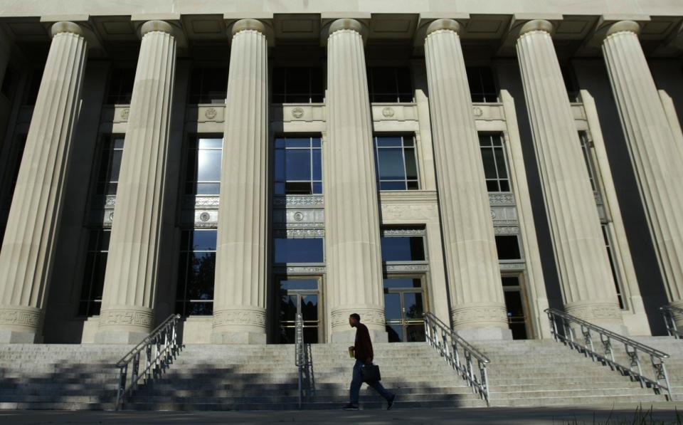 A University of Michigan student walks past the towering columns of the Angell Hall on Monday, June 23, 2003