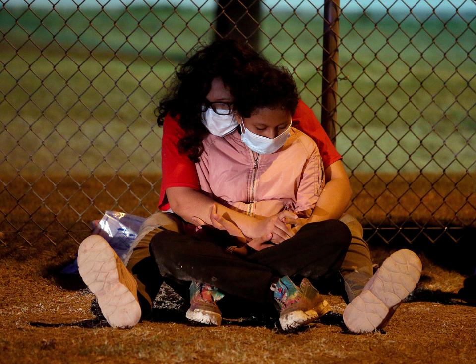 Immigrants detained by the US Border Patrol rest along the fence, Tuesday, May 17, 2022, in La Joya, Texas.