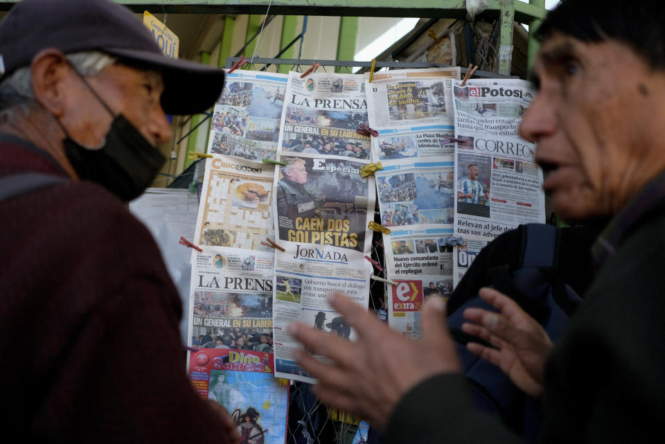 Hombres conversan frente a un quiosco de periódicos en La Paz, Bolivia, el jueves 27 de junio de 2024, un día después de que tropas del ejército irrumpieran en el palacio de gobierno en lo que el presidente Luis Arce llamó un intento de golpe. (AP Foto/Carlos Sánchez)
