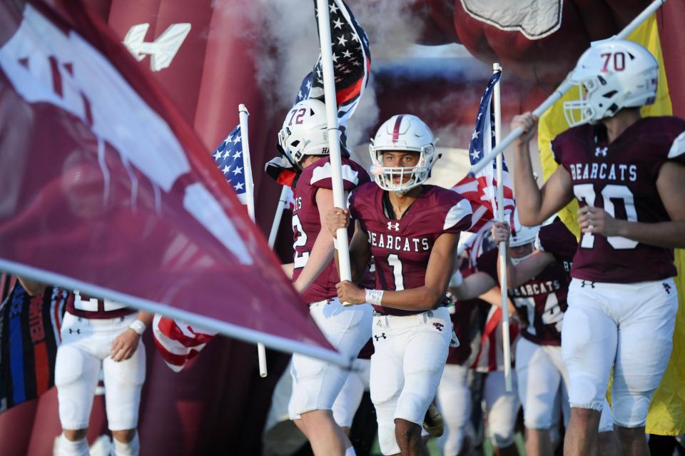 Hawley's Chandlin Myers runs onto the field holding a flag.