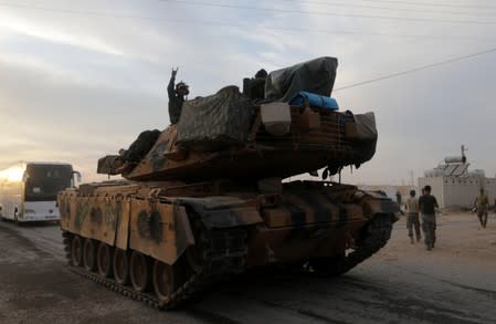 A Turkish soldier gestures as he rides on a military vehicle in the border town of Akcakale in Sanliurfa province