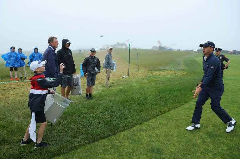 Justin Thomas of the US throws an autographed golf ball to a young fan during a practice round prior to the 2018 US Open, at Shinnecock Hills Golf Club in Southampton, New York, on June 13