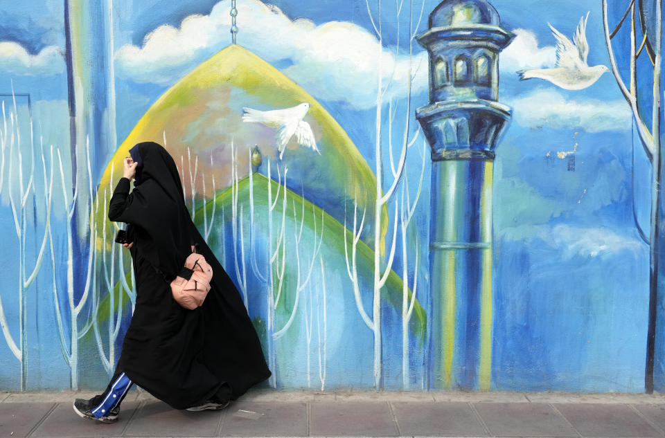 A head-to-toe veiled woman walks past a mural of a mosque, in downtown Tehran, Iran, Thursday, Feb. 22, 2024. Candidates for Iran's March 1, parliamentary election began campaigning Thursday in the country's first election since the bloody crackdown on the 2022 nationwide protests that followed the death of 22-year-old Mahsa Amini in police custody. (AP Photo/Vahid Salemi)