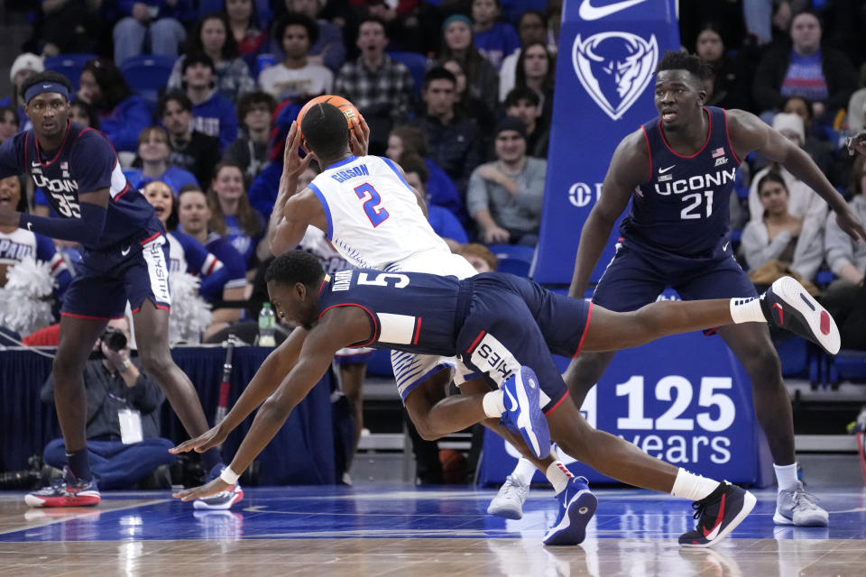 Connecticut's Hassan Diarra (5) fouls DePaul's Umoja Gibson (2) from behind during the first half of an NCAA college basketball game Tuesday, Jan. 31, 2023, in Chicago. (AP Photo/Charles Rex Arbogast)