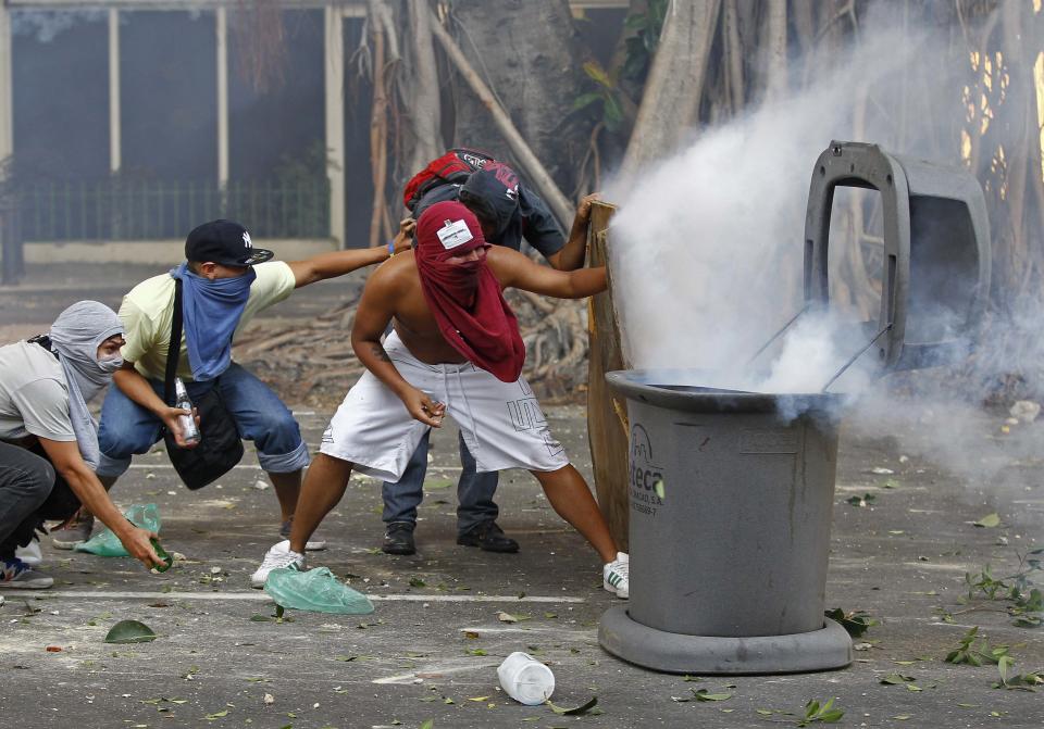 Demonstrators confront police after a tear gas grenade fell into a trash can, during a protest against the government of President Nicolas Maduro in Caracas, February 22, 2014. A female student and a young supermarket worker were the latest fatalities from Venezuela's political unrest as the death toll from 10 days of violence rose on Saturday to at least eight. REUTERS/Carlos Garcia Rawlins (VENEZUELA - Tags: CIVIL UNREST POLITICS)