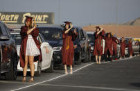 Graduates flip their tassels near their cars during a drive-thru graduation for Faith Lutheran High School at the Las Vegas Motor Speedway, Friday, May 22, 2020, in Las Vegas. The school held a special drive-thru graduation amid the coronavirus pandemic. (AP Photo/John Locher)