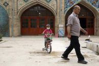 A girl wearing a protective face mask to help prevent the spread of the coronavirus rides her bicycle in the courtyard of a mosque, in the city of Zanjan, some 330 kilometers (205 miles) west of the capital Tehran, Iran, Sunday, July 5, 2020. Iran on Sunday instituted mandatory mask-wearing as fears mount over newly spiking reported deaths from the coronavirus, even as its public increasingly shrugs off the danger of the COVID-19 illness it causes. (AP Photo Vahid Salemi)