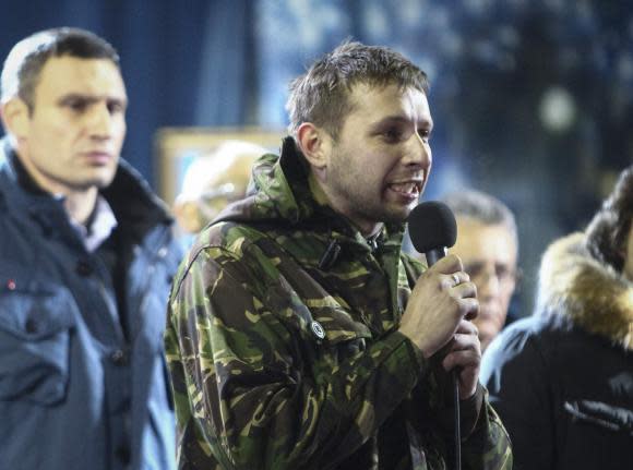 Anti-presidential protester Volodymyr Parasiuk addresses the crowd as opposition leader Vitaly Klitschko (L) looks on during a rally in Kiev February 21, 2014. When the history of the bloody turbulence in Ukraine is written, 26-year-old Parasiuk who learned combat skills in the army cadets may be recorded as the man who made up Viktor Yanukovich's mind to cut and run. To match Insight UKRAINE-CRISIS/HERO   Picture taken February 21, 2014.  REUTERS/Vitaliy Nosach (UKRAINE - Tags: POLITICS CIVIL UNREST PROFILE)