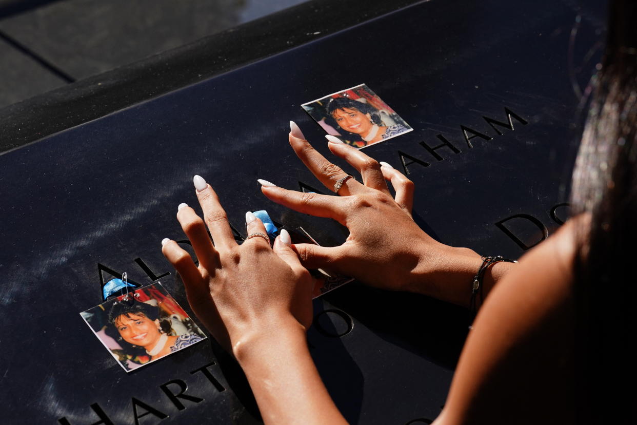 A woman places photos of a relative on the 9/11 Memorial. 