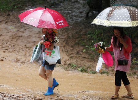 Family members carry flowers to pray near the Tham Luang cave complex during a search for members of an under-16 soccer team and their coach, in the northern province of Chiang Rai, Thailand, June 27, 2018. REUTERS/Soe Zeya Tun