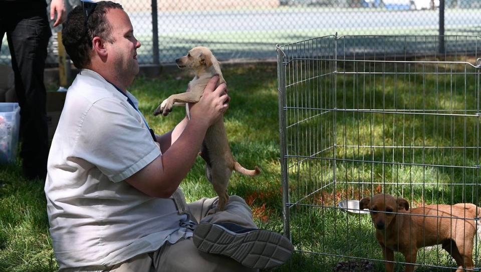 Stanislaus Animal Services Agency volunteer Craig Boyer plays with a shelter dog during the 2023 Earth Day celebration at Graceada Park in Modesto.