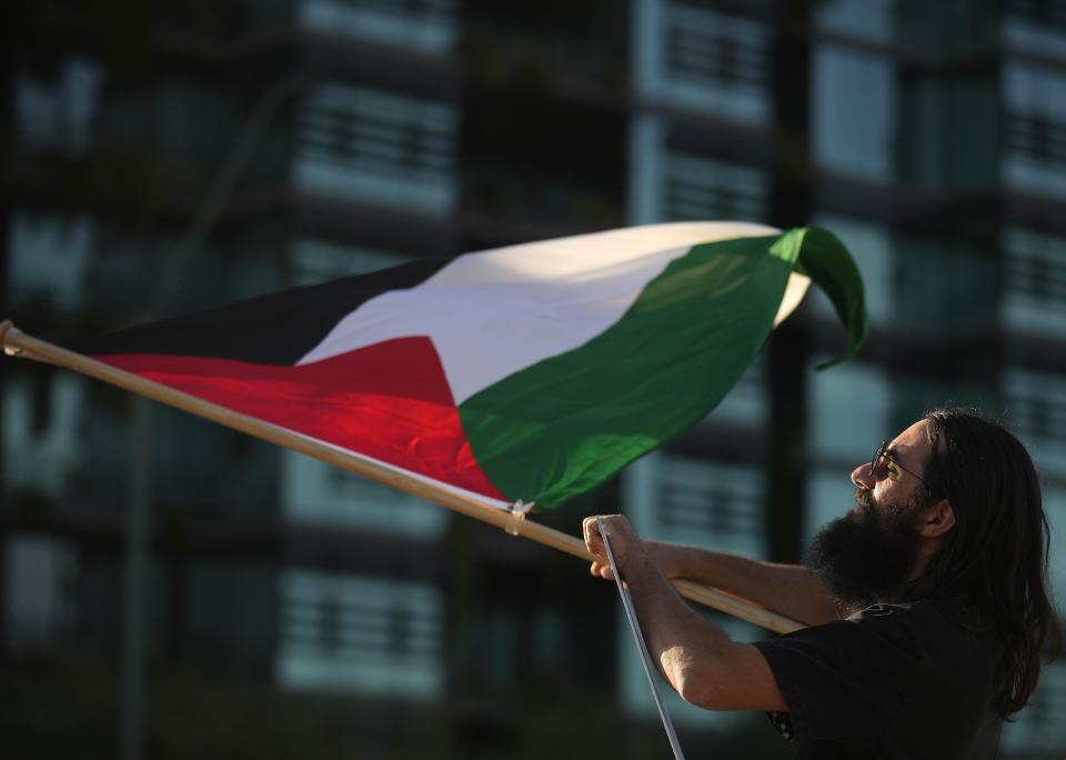 Rumsey Salman waves a Palestinian flag as the group cross the intersection during a Free Palestine protest at the corner of Scottsdale Road and Greenway-Hayden Loop on March 22, 2024.